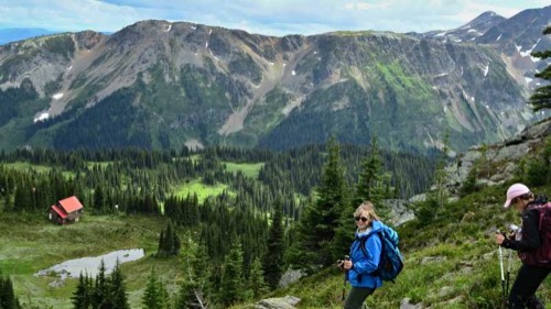 Hikers on a mountainside trail overlooking a valley